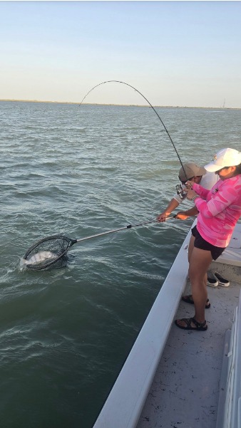 Angler braces a sharply bent rod from the boat bow.