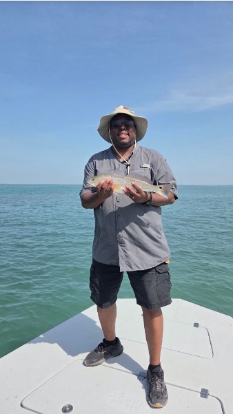 Captain holds a fresh fish on the bow.