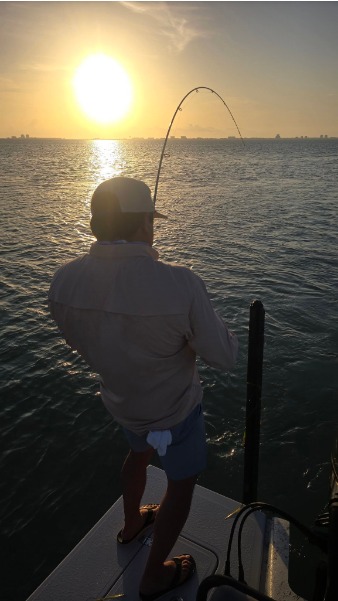 Sunset hookup silhouette with rod deeply bent.