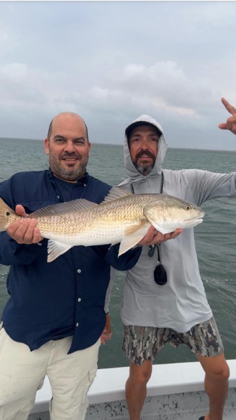 Two anglers hold a large fish together.