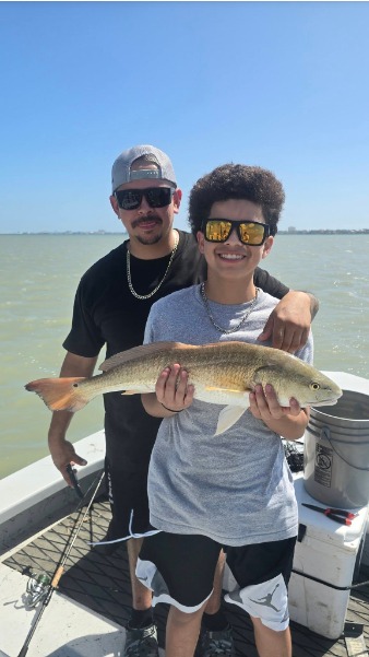 Two anglers hold their catch on the boat.