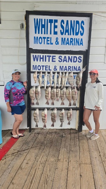 Anglers pose beside a large fish stringer.