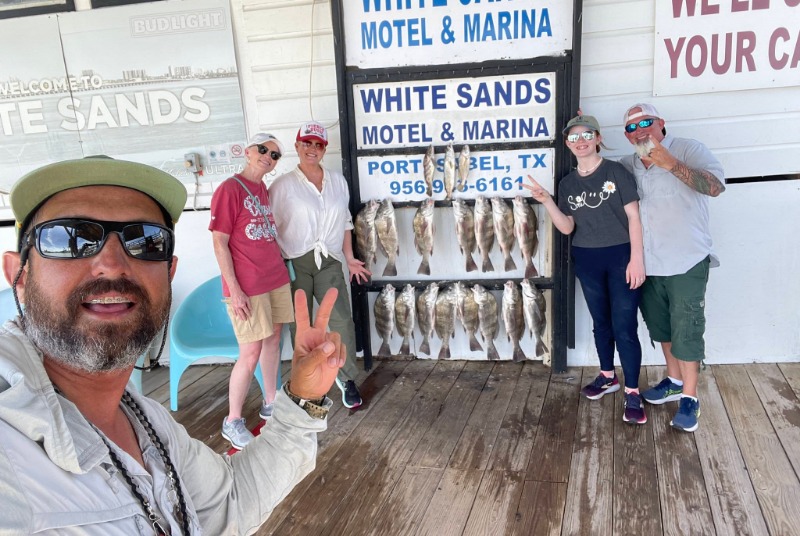 Group selfie with a full fish cleaning board.